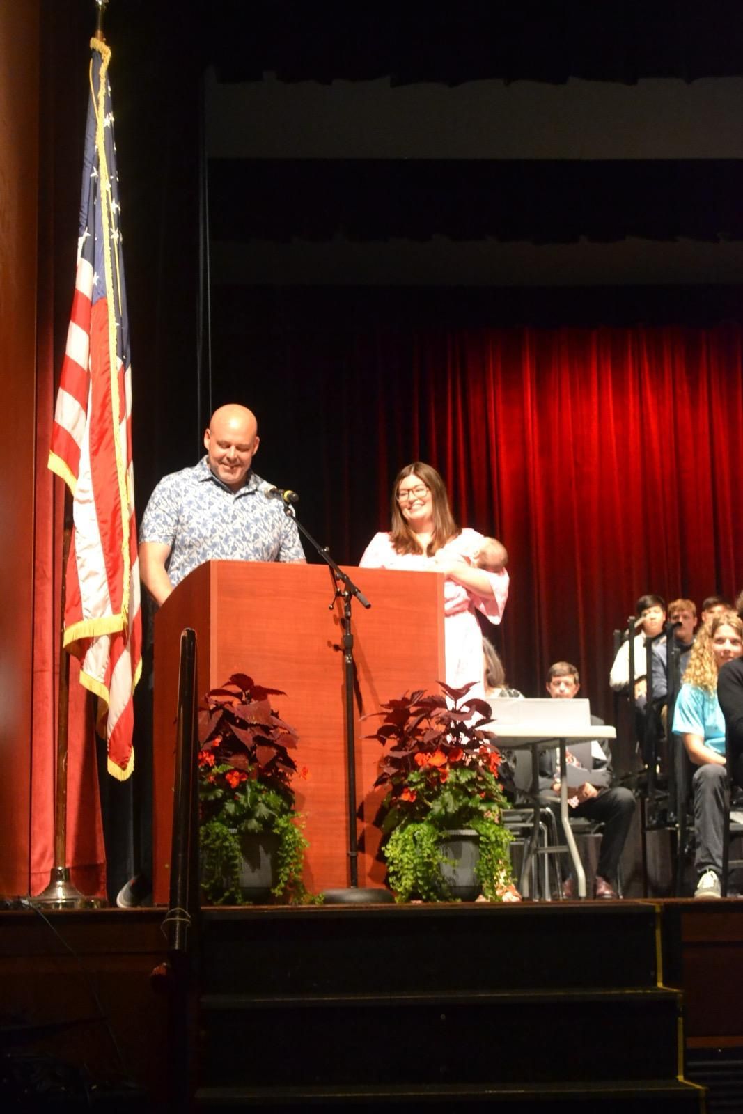 A man and a woman are standing at a podium on a stage.