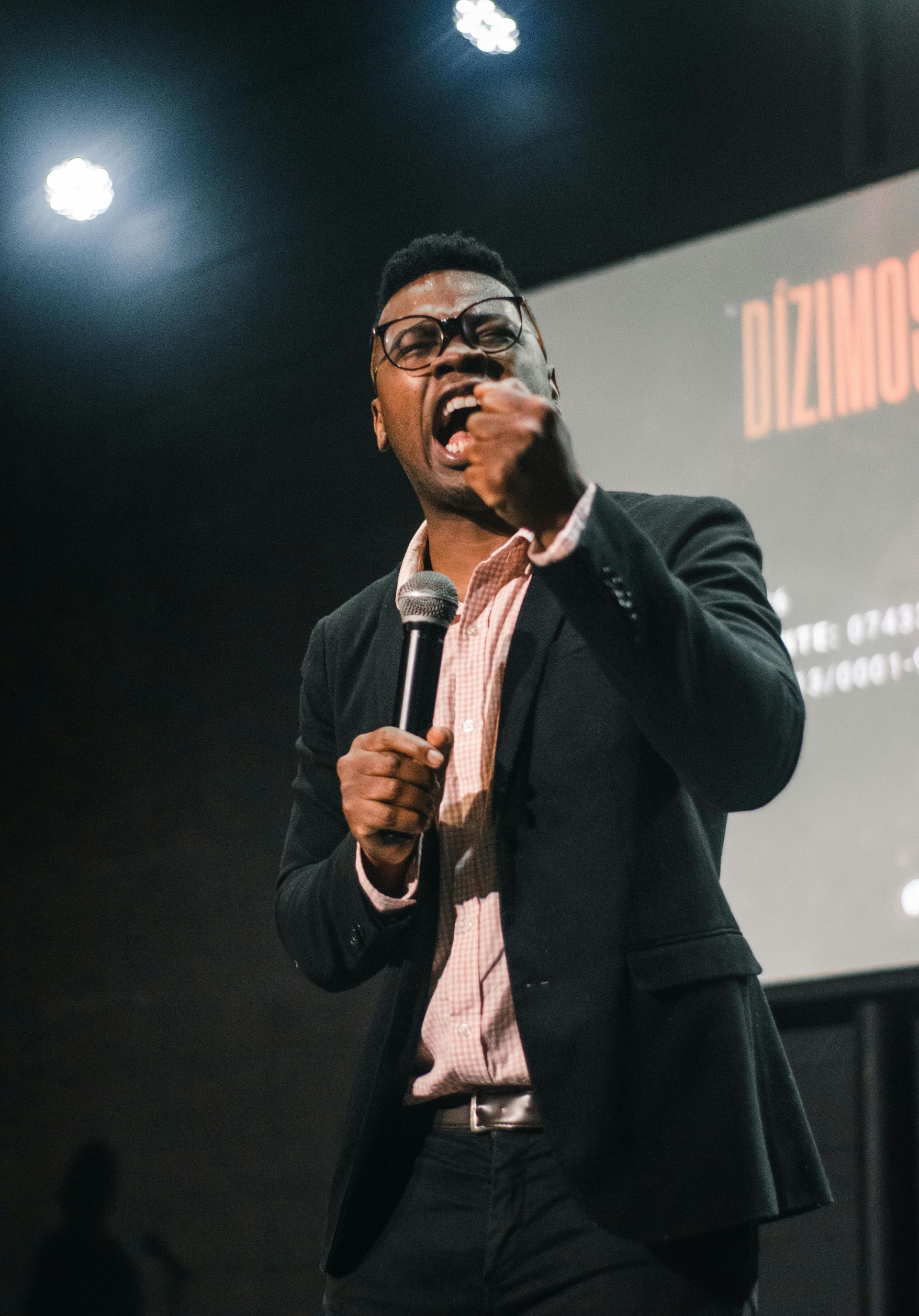 A man in a suit is speaking into a microphone on a stage.
