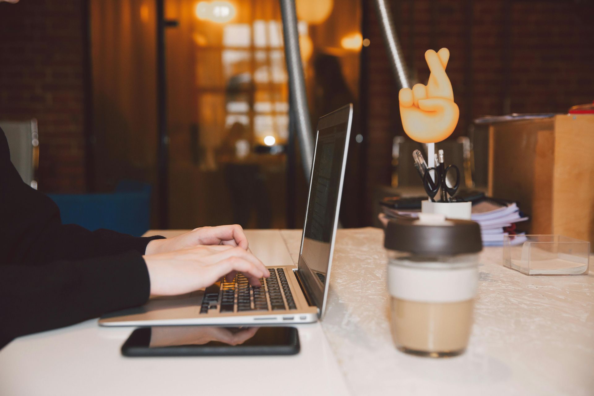 A person is typing on a laptop next to a cup of coffee.