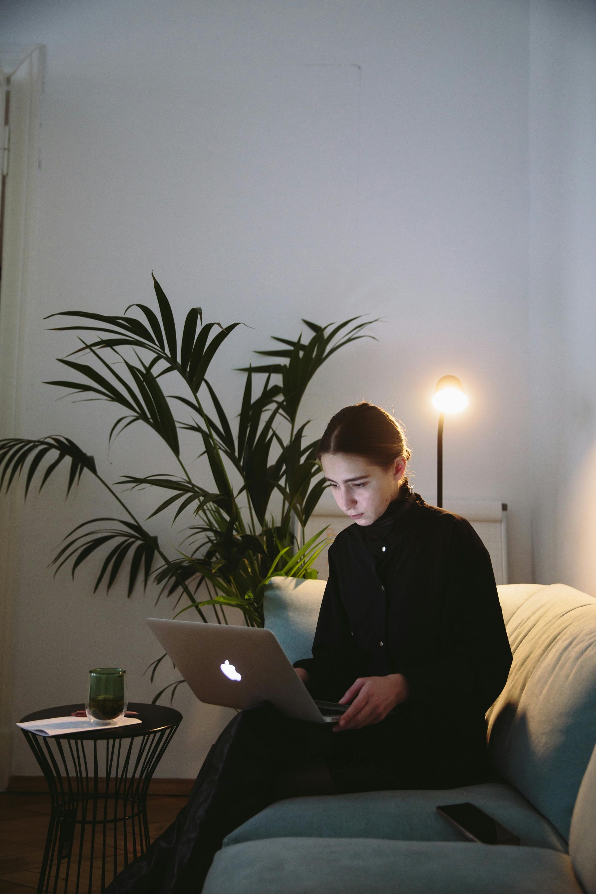 A group of people are sitting around a table with laptops and phones.