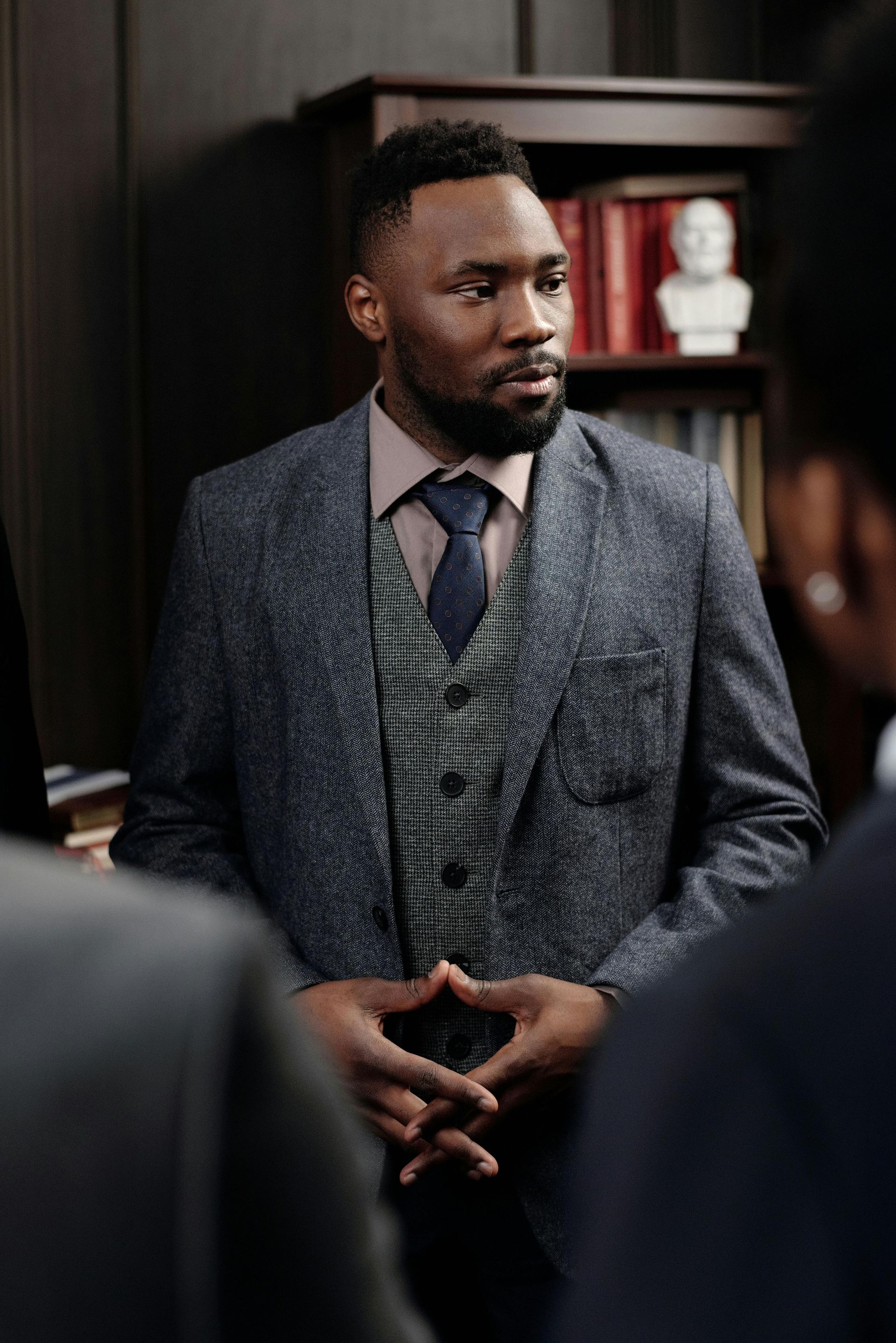 A man in a suit and tie is standing in a room with other people.
