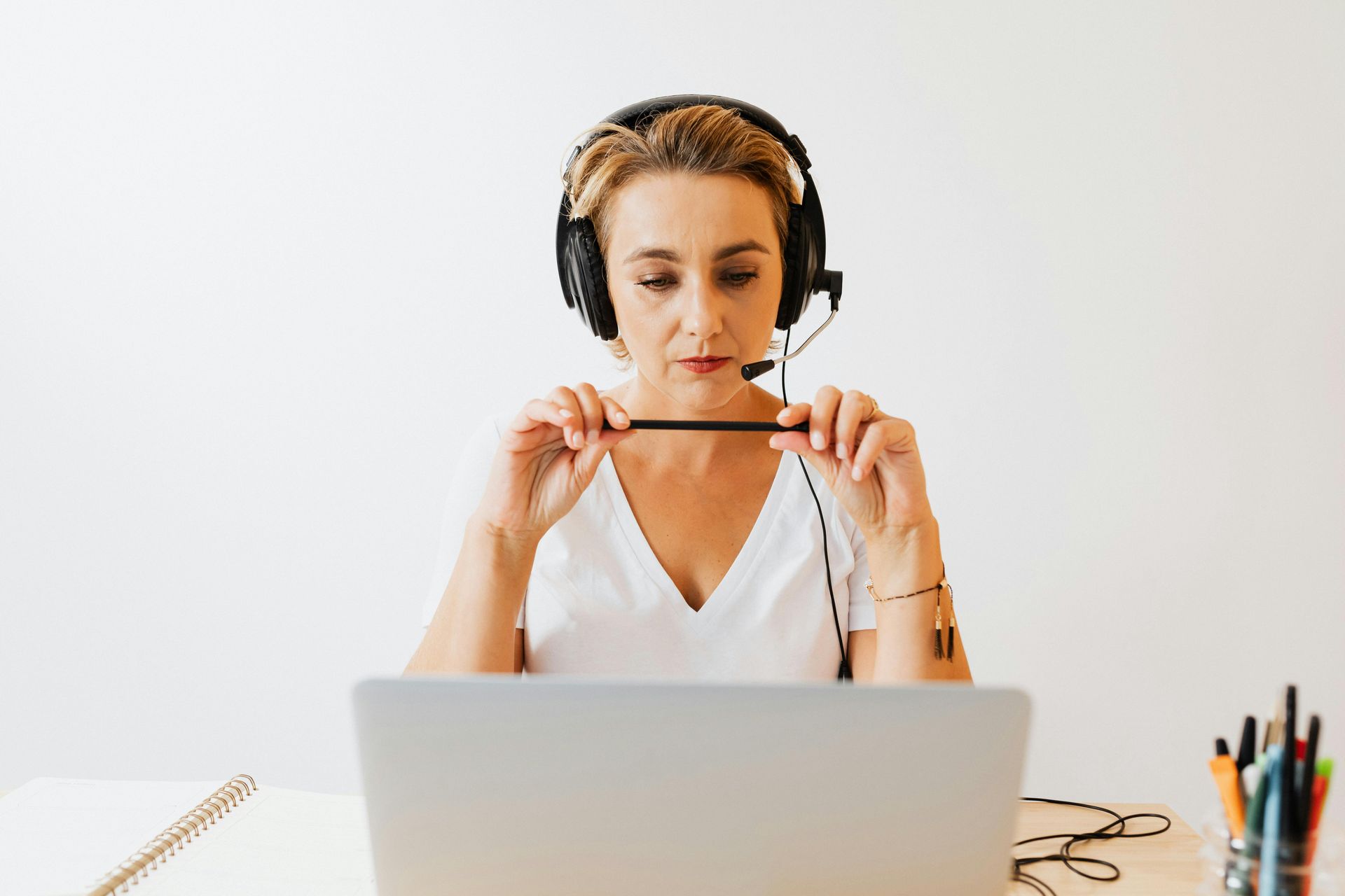 A woman wearing headphones and a microphone is sitting in front of a laptop computer.