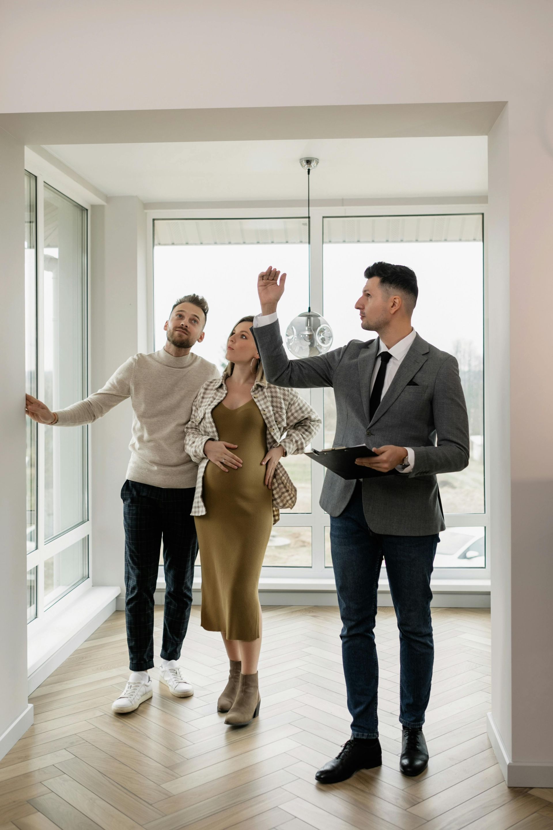 A man and a woman are looking at a house with a real estate agent.