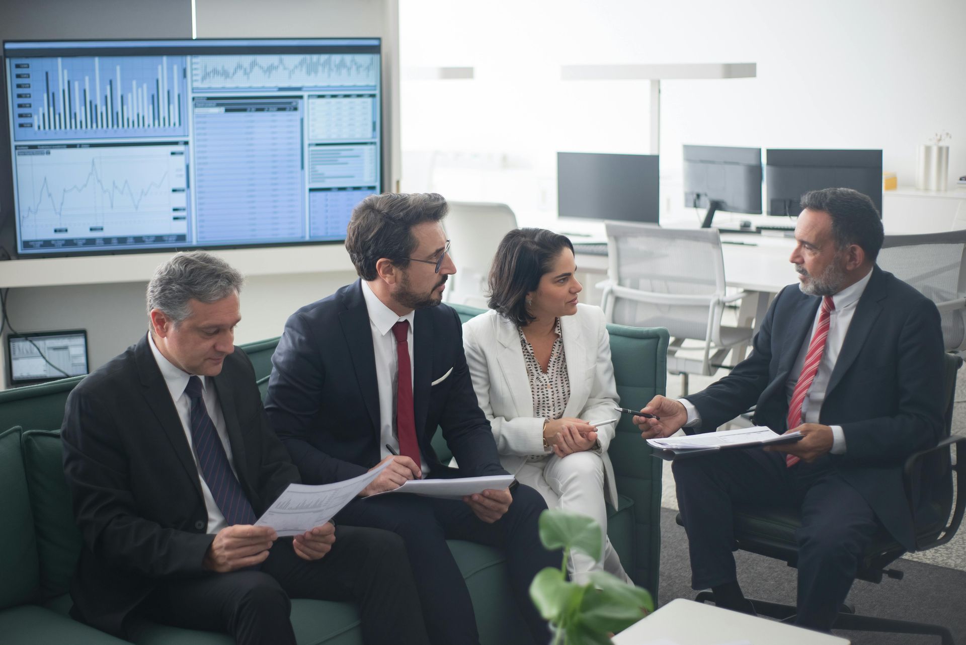 A group of business people are sitting on a couch having a meeting.