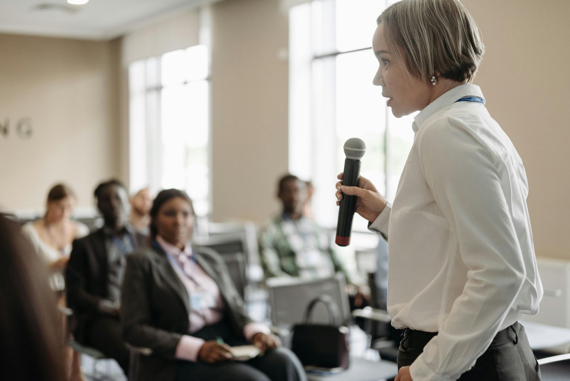 A woman is holding a microphone in front of a group of people.