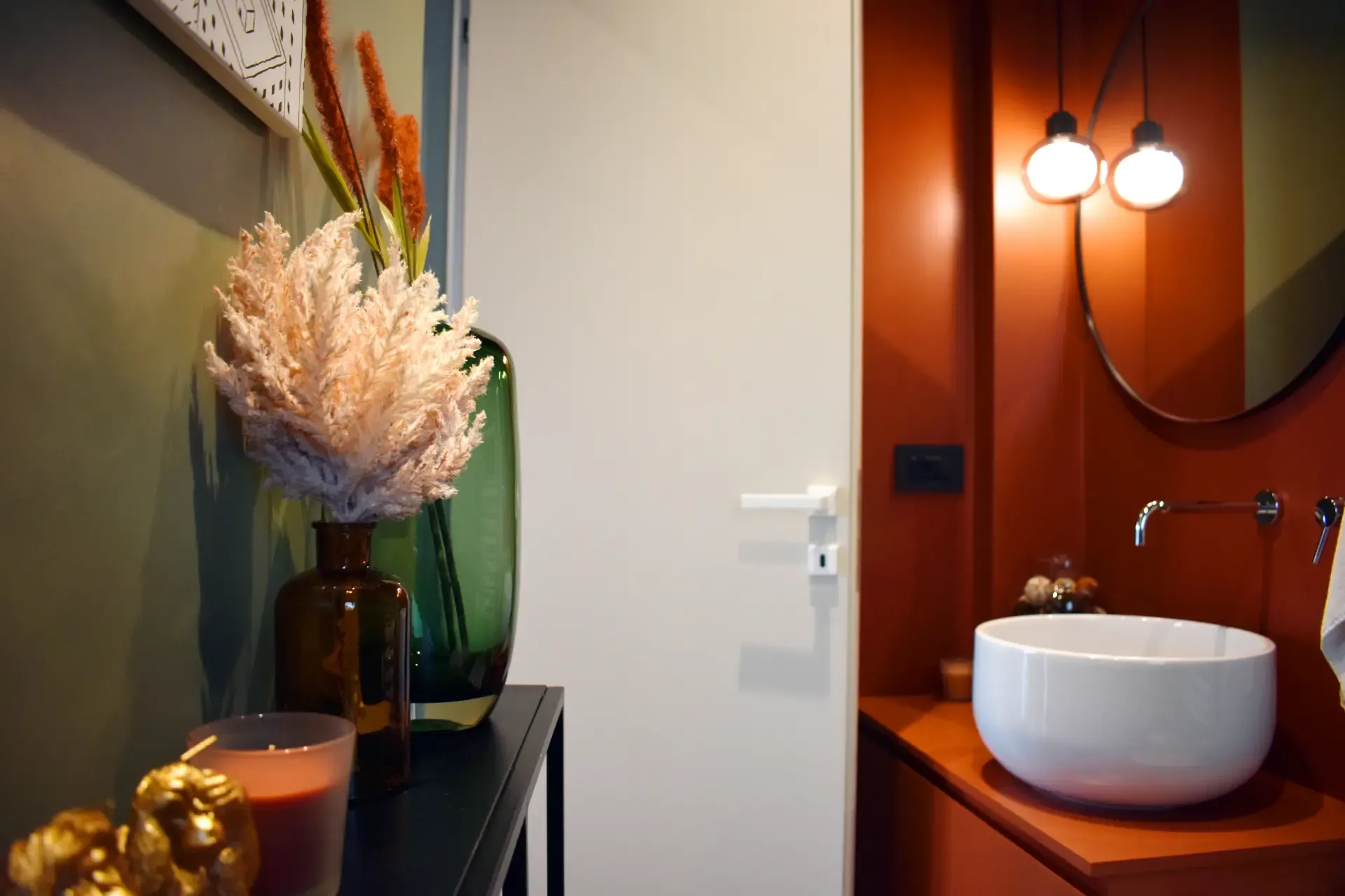 Interno con lavandino bianco, parete arancione e fiori decorativi in vasi.