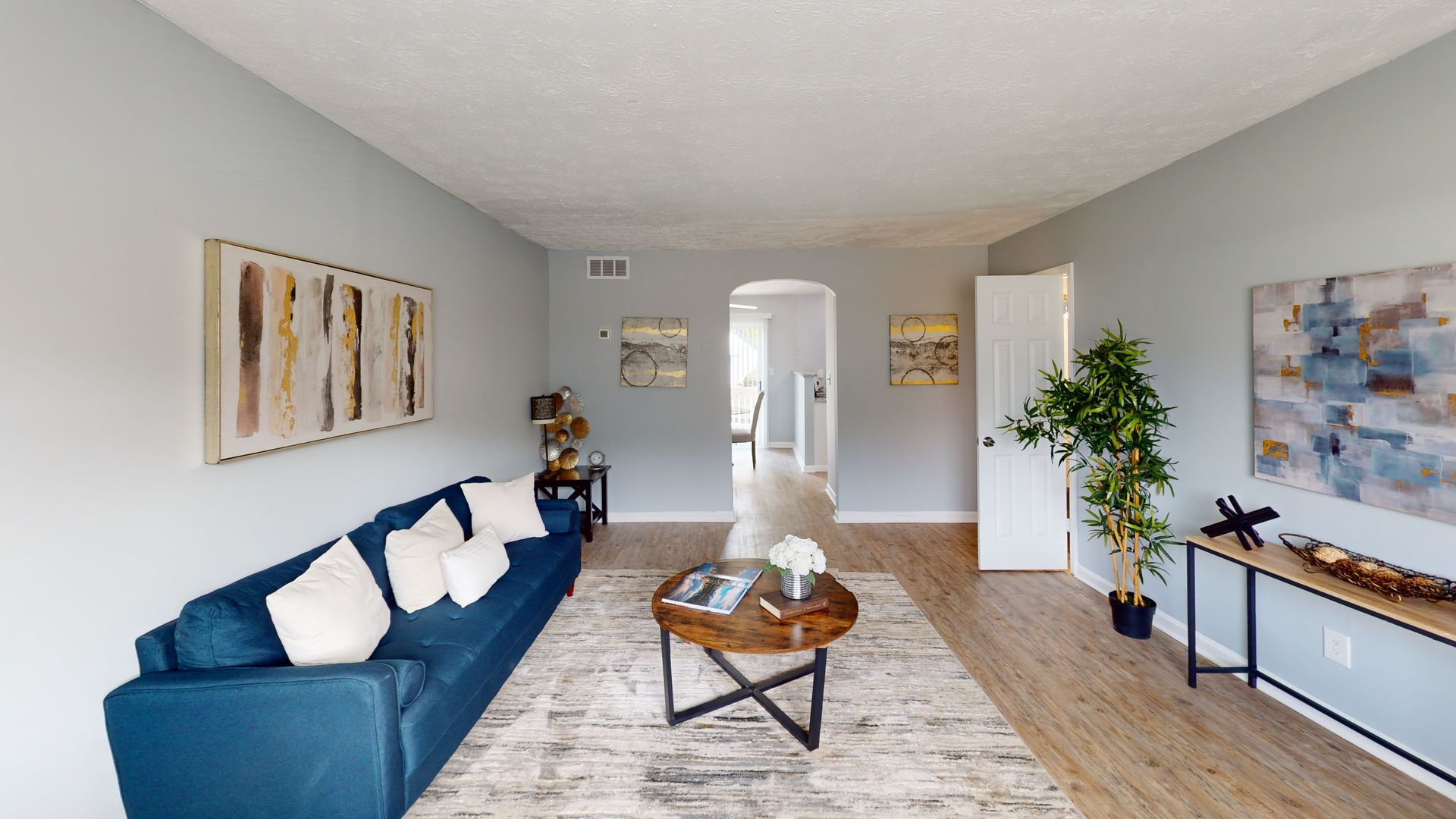 Empty room with wood-look flooring, white walls, open door, and window.