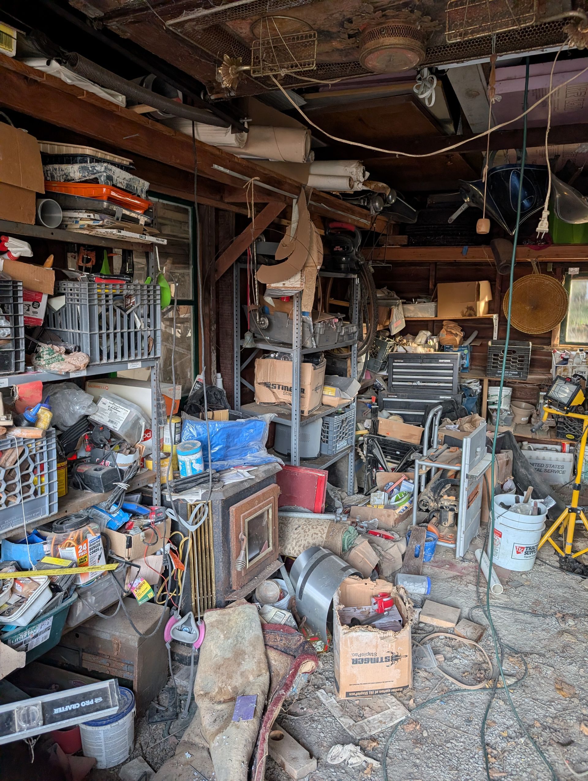 Messy garage interior, cluttered with tools, boxes, and various objects.
