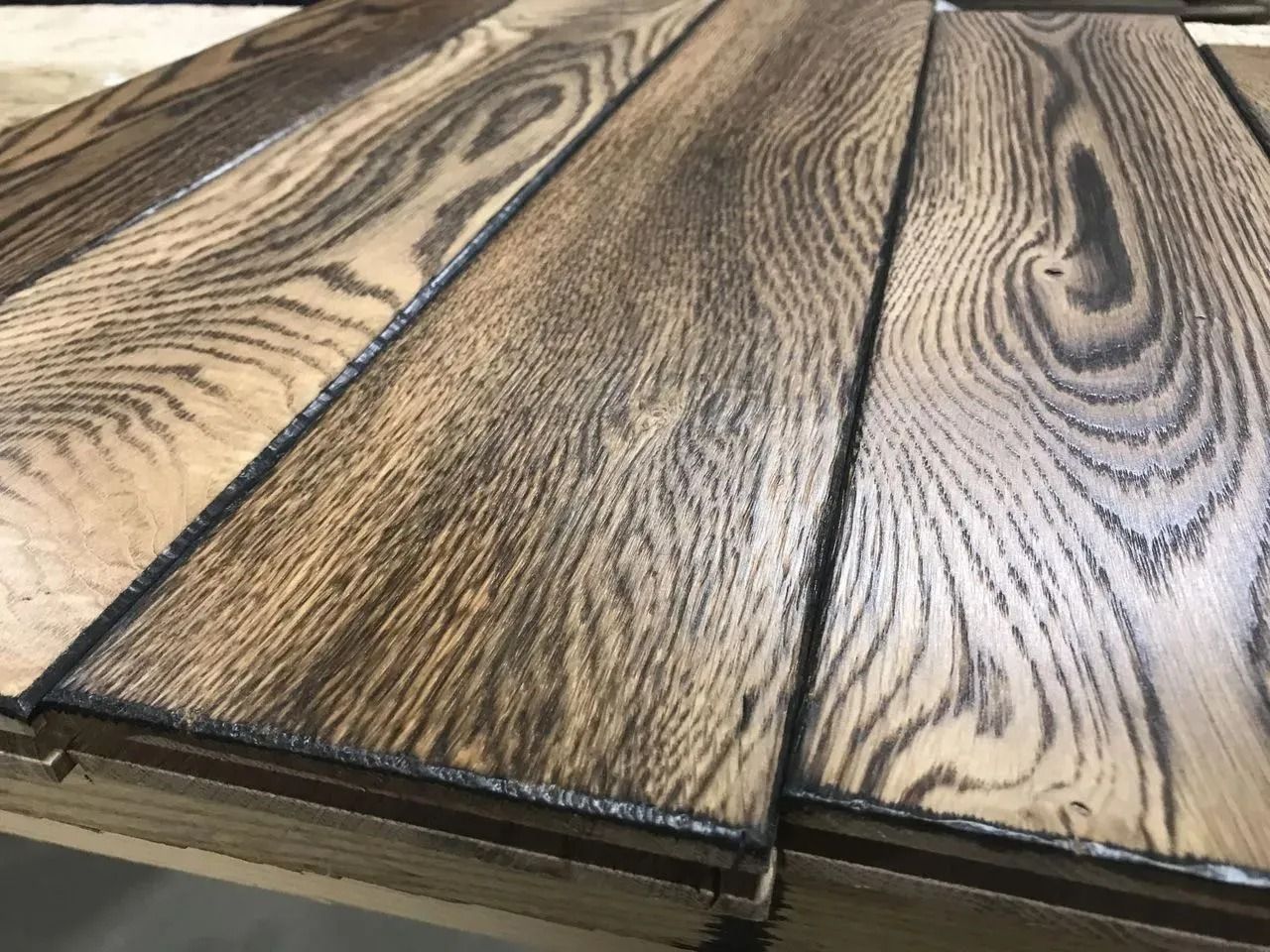 Close-up of wood-grain laminate planks with dark seams on a tabletop or floor sample.