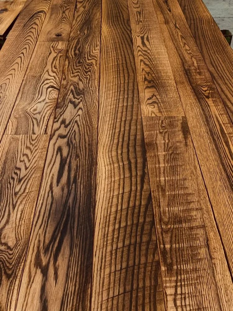 Close-up of a rustic wooden tabletop with dark, wavy grain patterns and warm brown tones