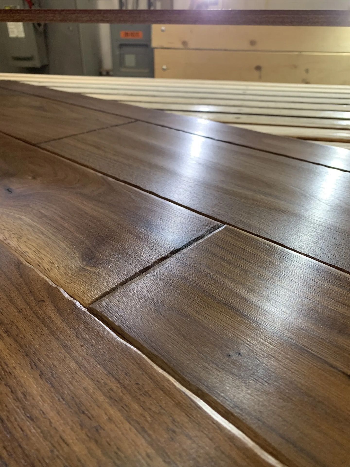 Close-up of glossy wooden floorboards with visible seams and grain in a workshop setting