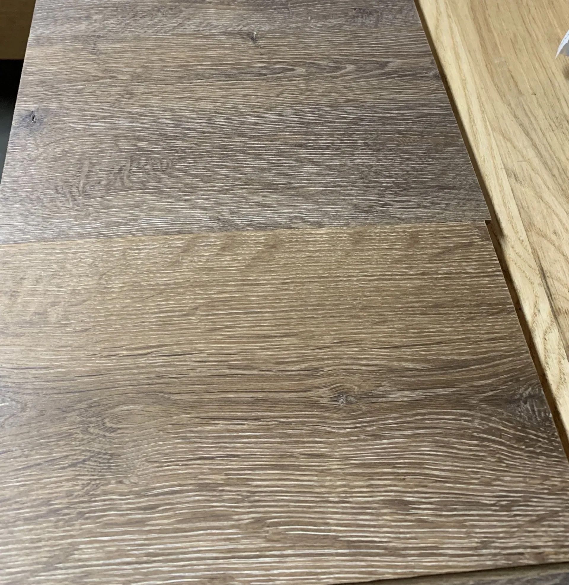 Close-up of two wood-grain floor or tabletop panels with a seam between them.