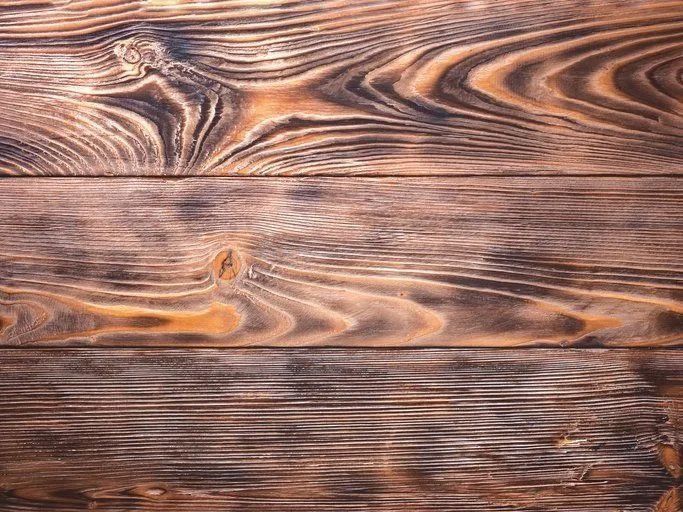 Brown wooden plank surface with swirling grain patterns and a weathered texture