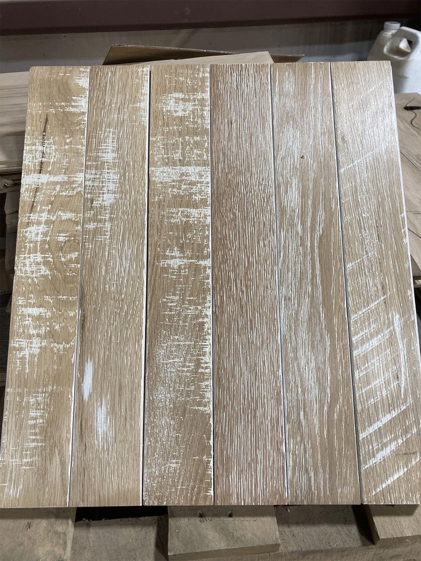 Five weathered gray-brown wooden planks laid side by side on a concrete floor