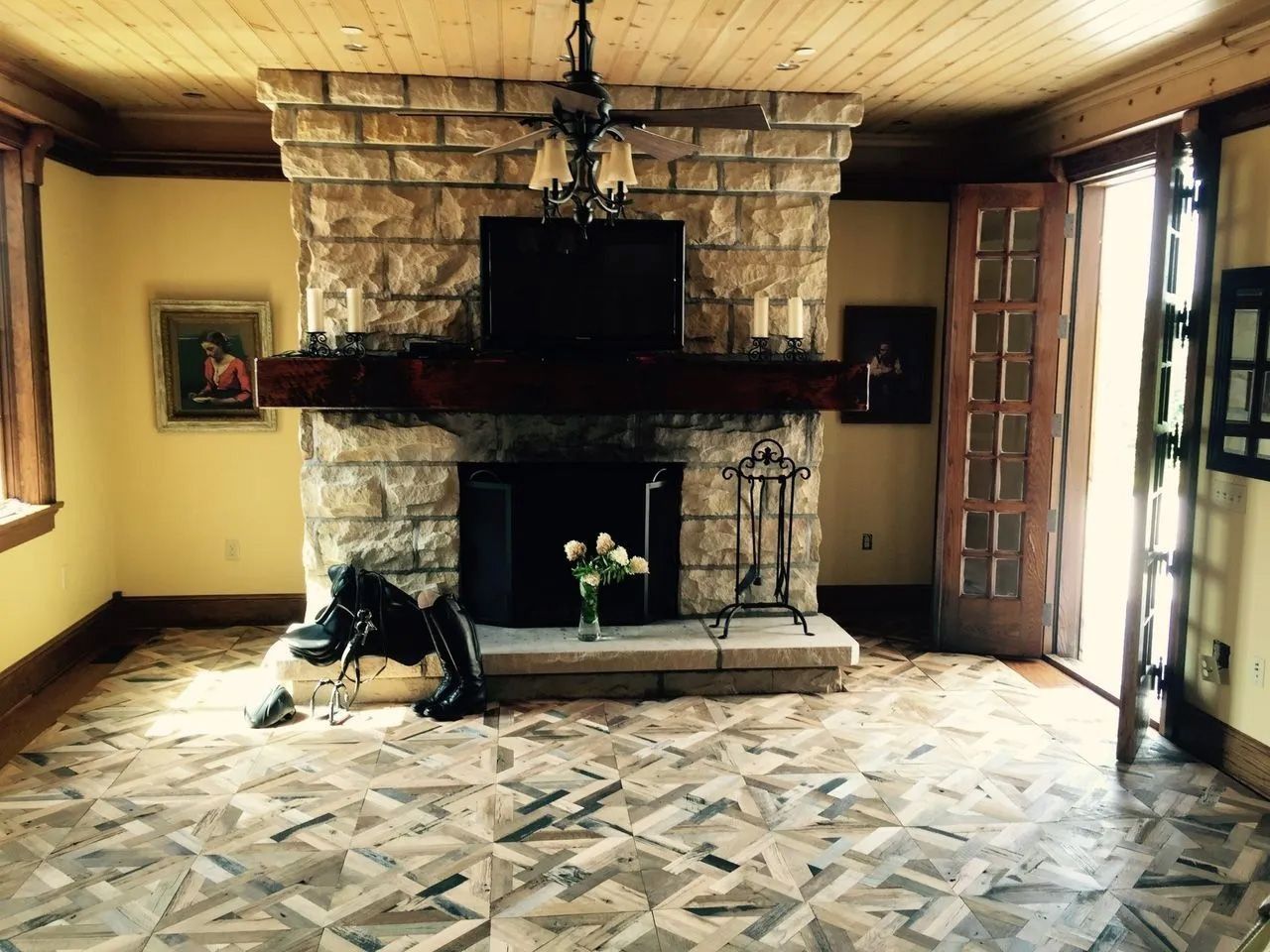 Rustic living room with stone fireplace, patterned tile floor, and a dog resting by the hearth
