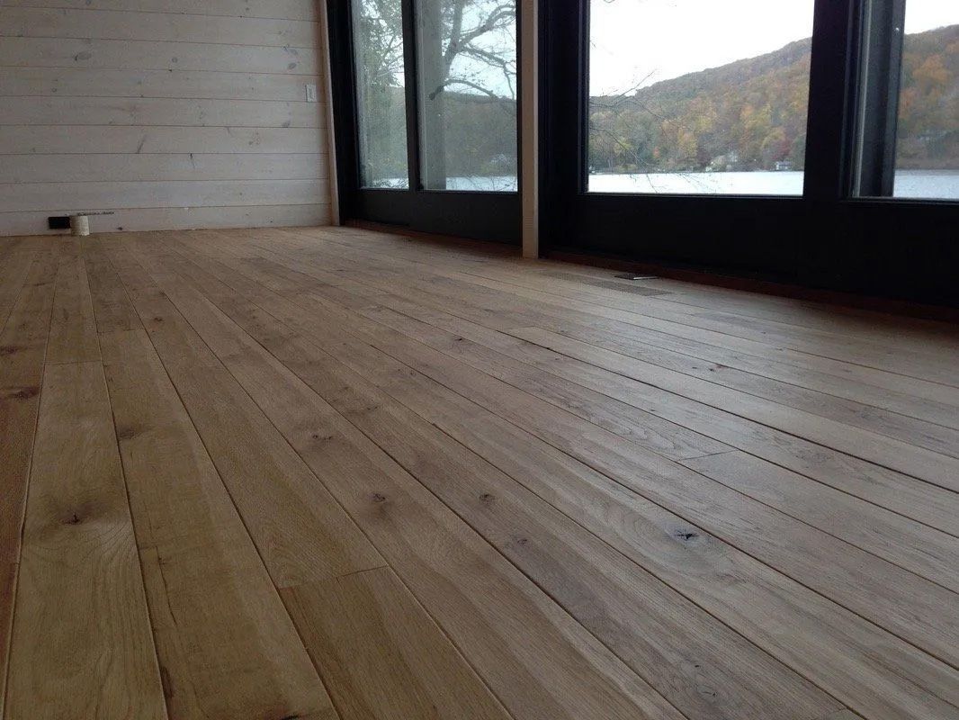 Wooden floor in a modern room with large windows overlooking a snowy landscape