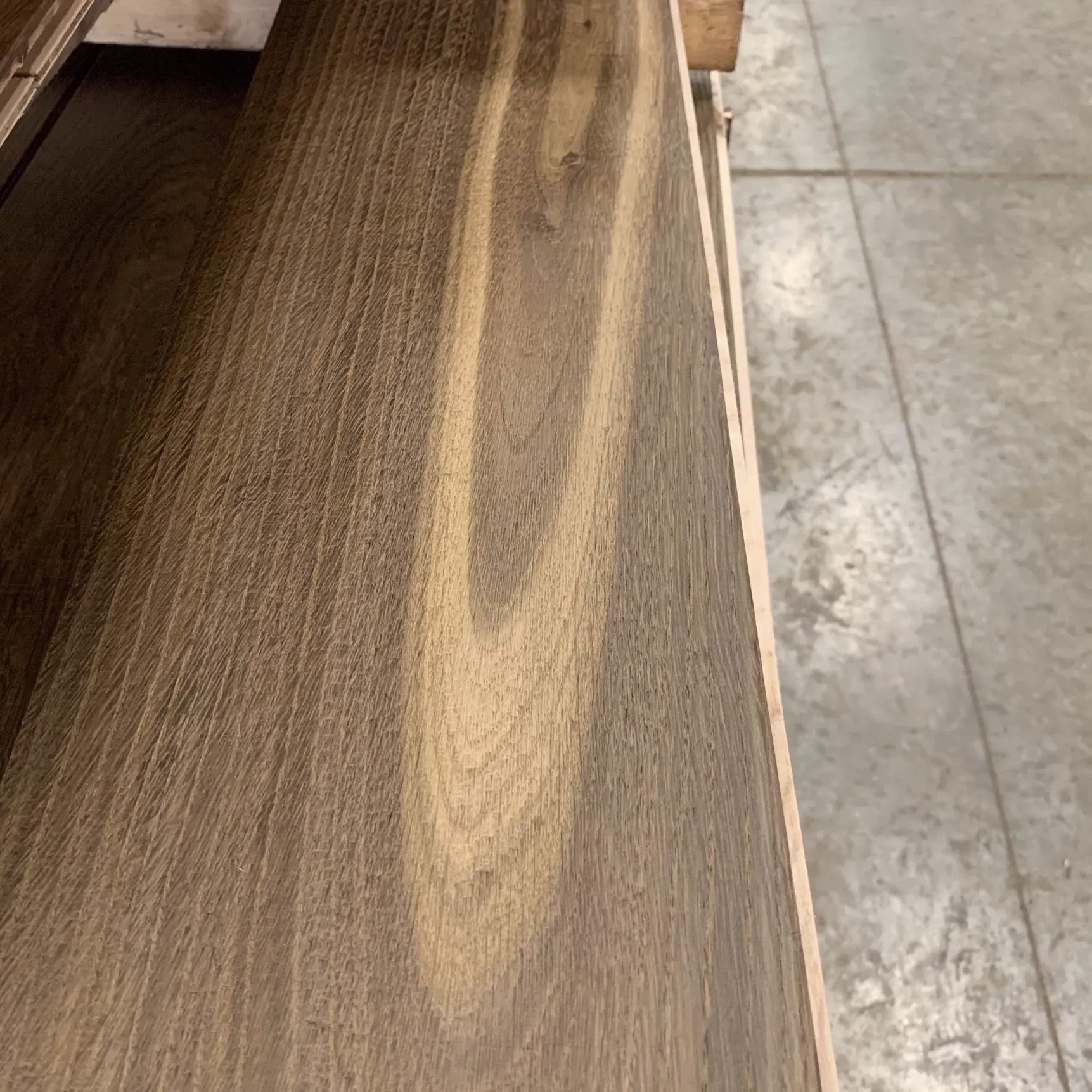 Wood-grain wooden tabletop beside a gray tiled floor