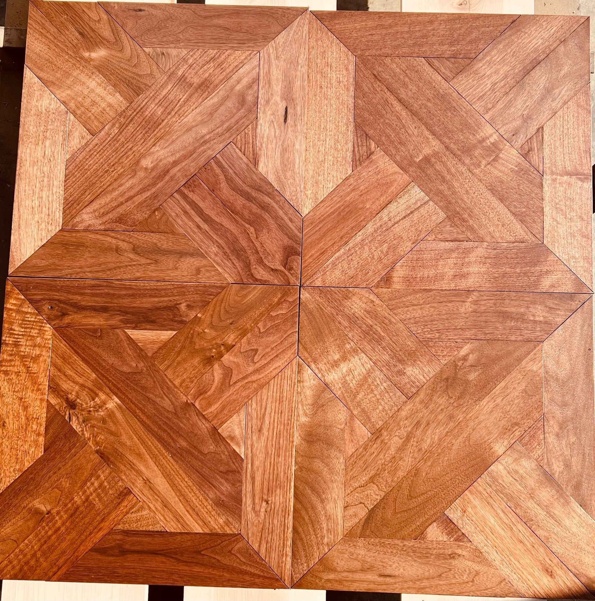 Close-up of a square wooden parquet panel with geometric grain patterns in warm brown tones