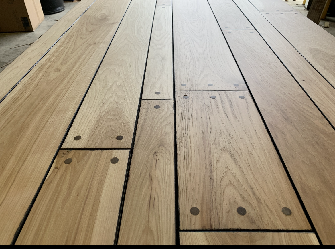 Light wood floorboards with black metal rivets in a low-angle indoor view