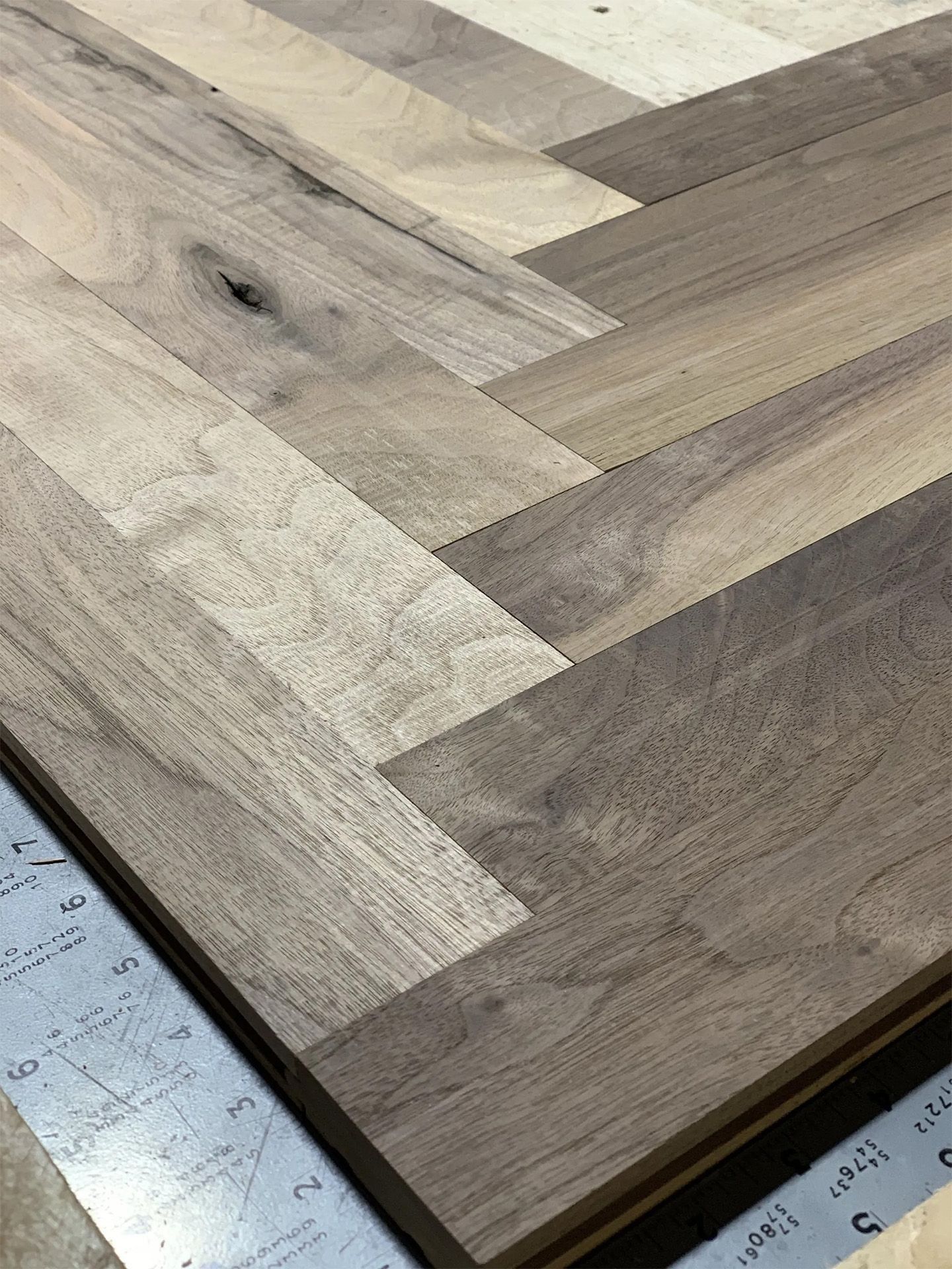 Close-up of a wooden herringbone tabletop with light and dark wood tones on a measuring surface.
