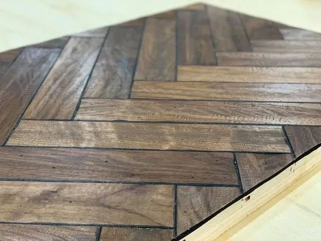 Diagonal herringbone wood floor with brown planks and a light border edge