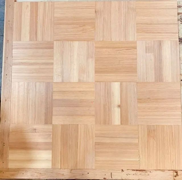 Close-up of a light wood parquet floor with a square woven tile pattern
