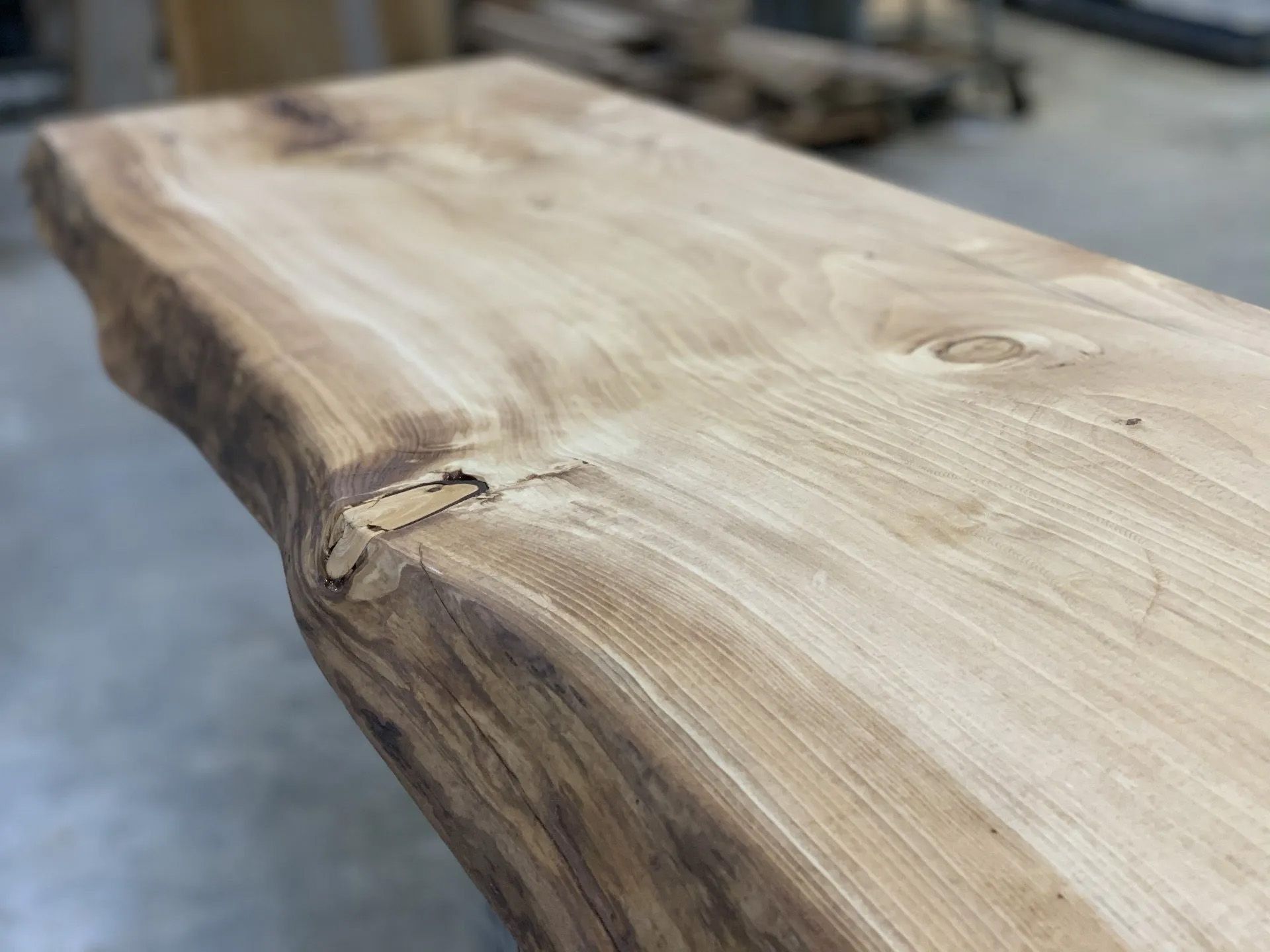 Rough live-edge wooden slab tabletop with natural grain and bark edge
