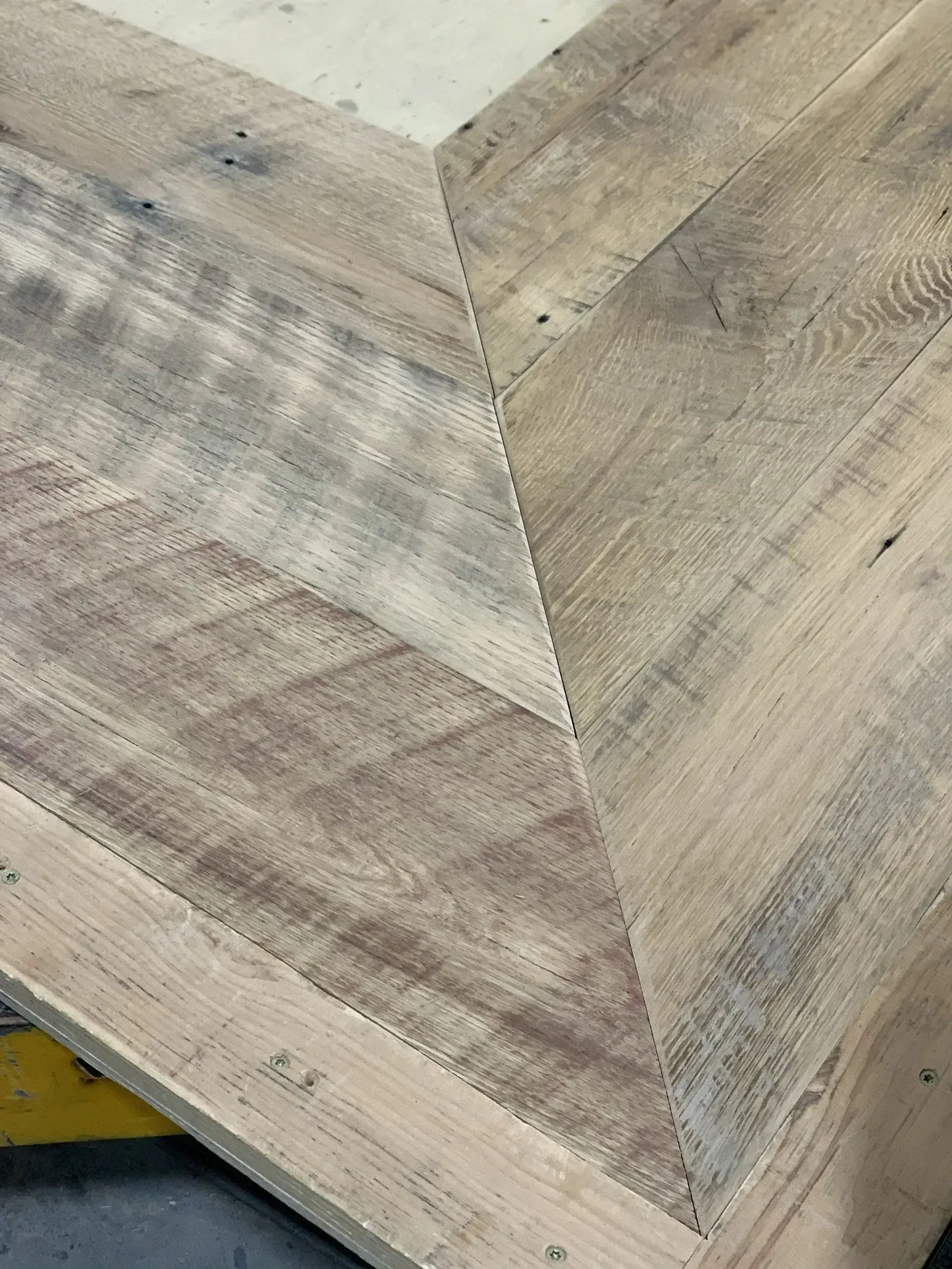 Close-up of a light wood herringbone floor with visible grain and seams