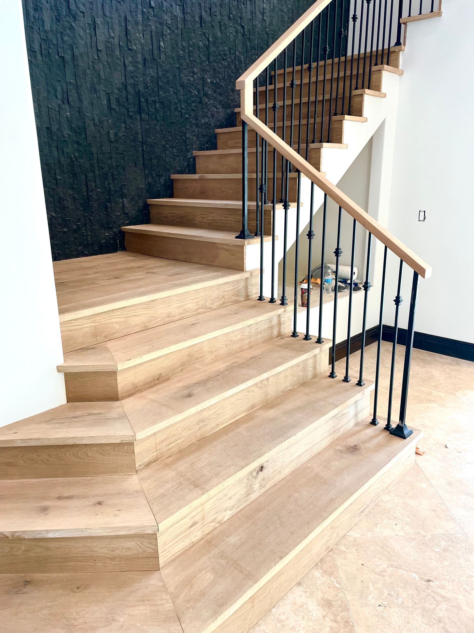 Modern wooden staircase with black metal railing and dark textured accent wall