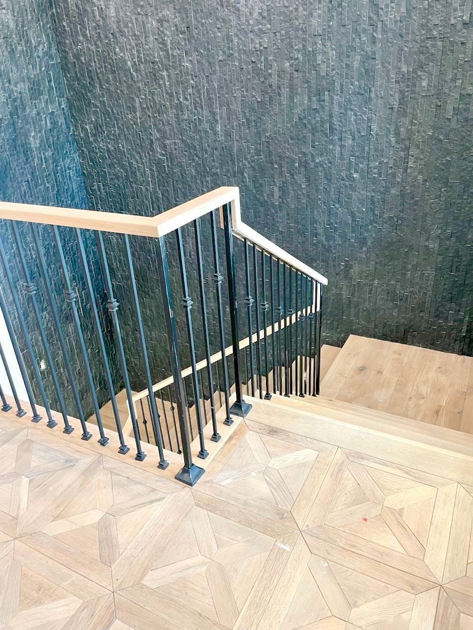 Indoor staircase with beige patterned tile, dark blue railing, and textured blue wall