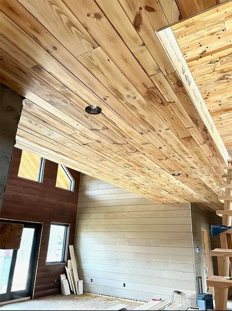 Interior under construction with wood plank ceiling, tall wall panels, and windows letting in daylight