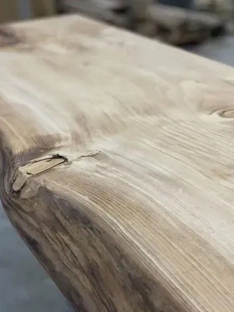 Close-up of a smooth, pale wooden surface with a knot and visible grain lines