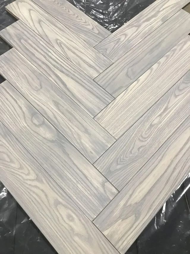 Gray wood-look herringbone floor planks laid over a dark protective covering