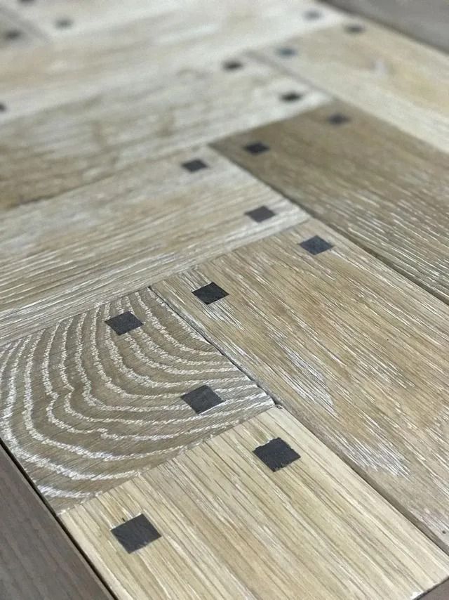 Close-up of a light wood parquet floor with dark square inlay accents.