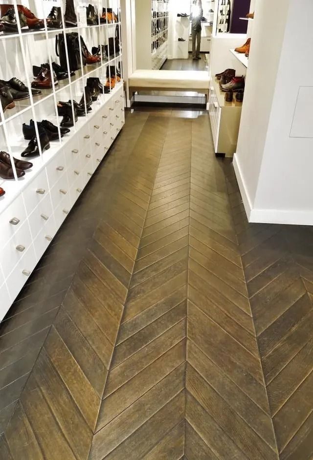 Shoe store aisle with herringbone wood floor and rows of shoes on white shelves