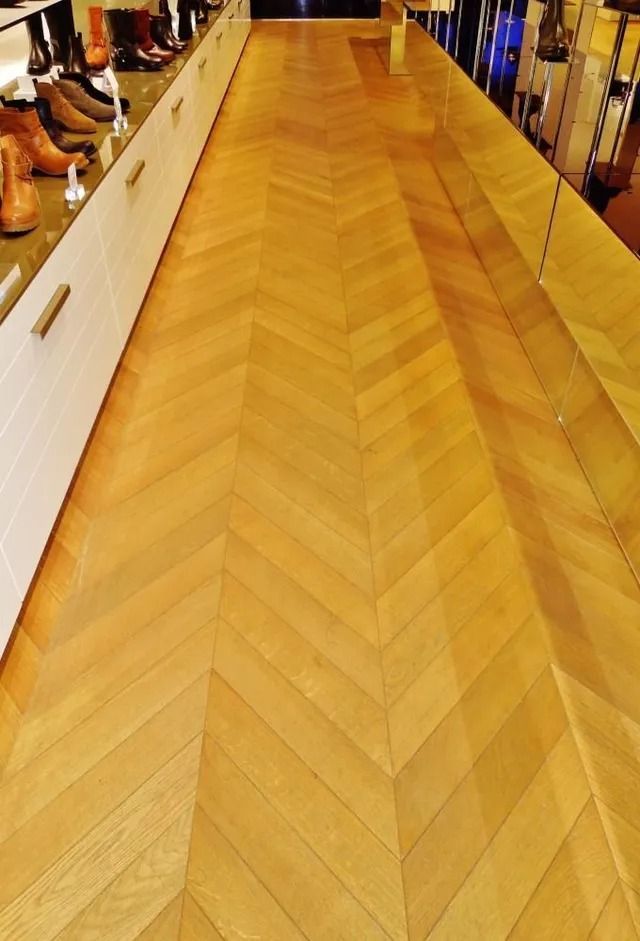 Wooden herringbone floor display in a showroom or store aisle, with shoes along the sides