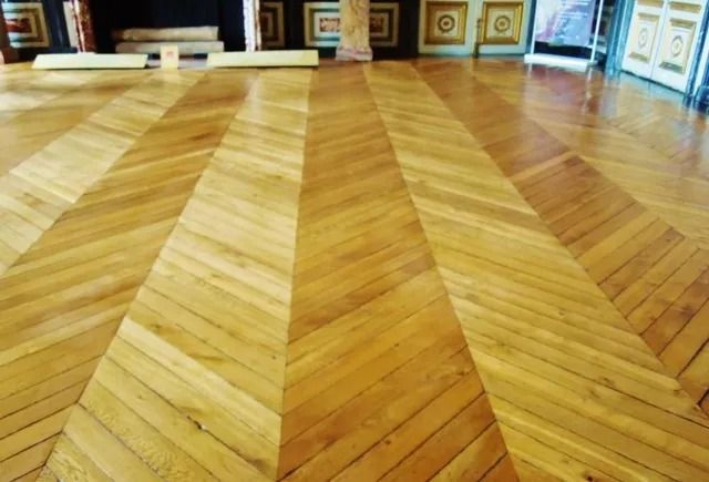 Polished herringbone wood floor in a room with framed artwork along the walls