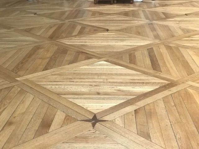 Wooden parquet floor with a geometric starburst pattern and a central diamond design.