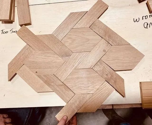 Interwoven light wood puzzle pieces arranged in a geometric knot pattern on a workbench