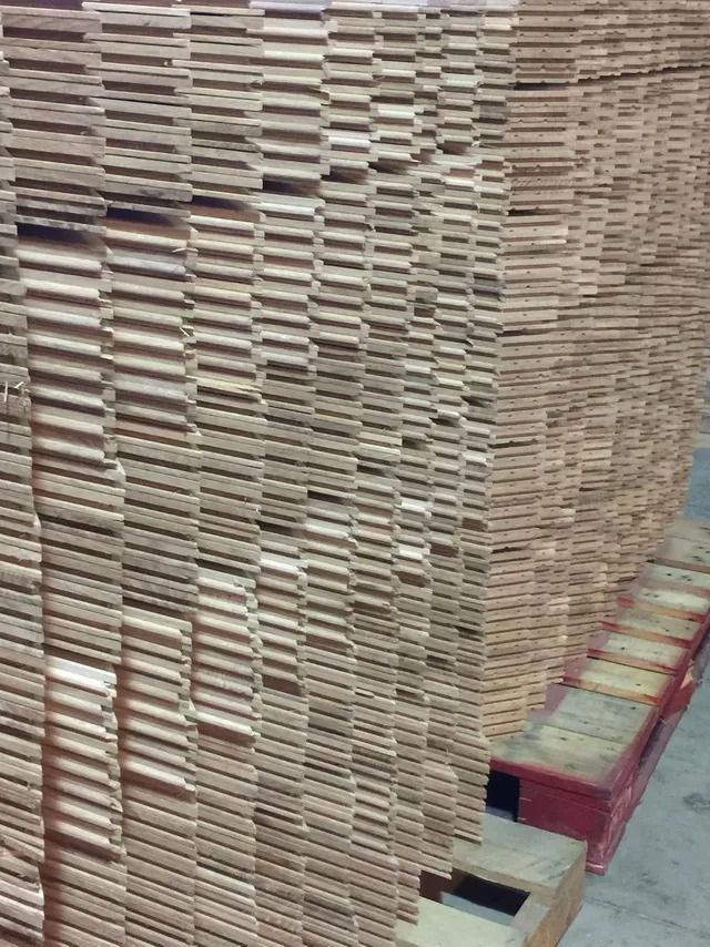 Stacks of cut cardboard sheets on a red pallet in a warehouse.