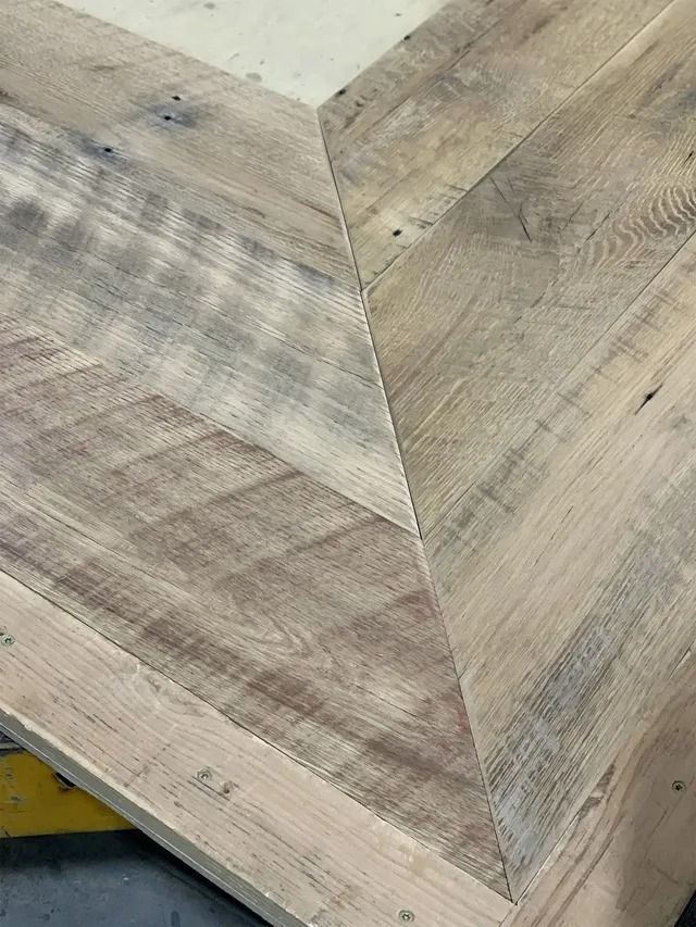 Close-up of a light wood tabletop with a geometric chevron pattern and weathered grain