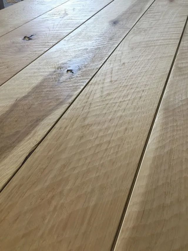 Close-up of a light wood floor with visible grain and a few small marks.