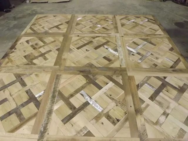 Wooden crate panels with crisscross slats stacked on a concrete floor in a warehouse.
