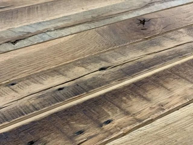 Weathered wooden planks with knots and grain lines, shown in a close-up view.