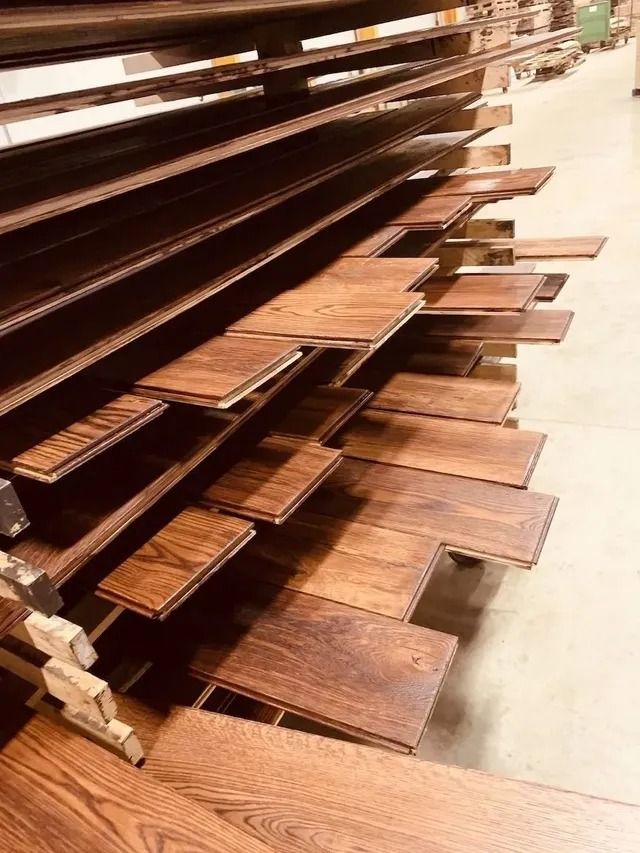 Stacked wooden shelves or boards with metal brackets in a workshop or lumberyard.
