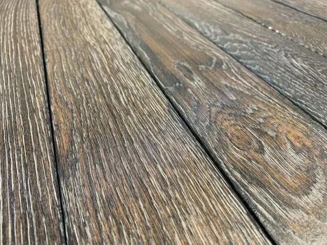 Weathered wooden floorboards with gray-brown grain and visible knots, viewed close up.