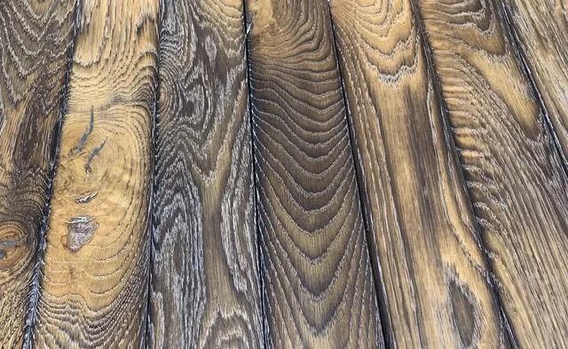Close-up of weathered wooden planks with dark grain and knots in brown and gray tones