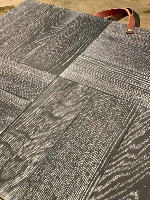 Gray textured carpet tiles with a tan leather strap on top