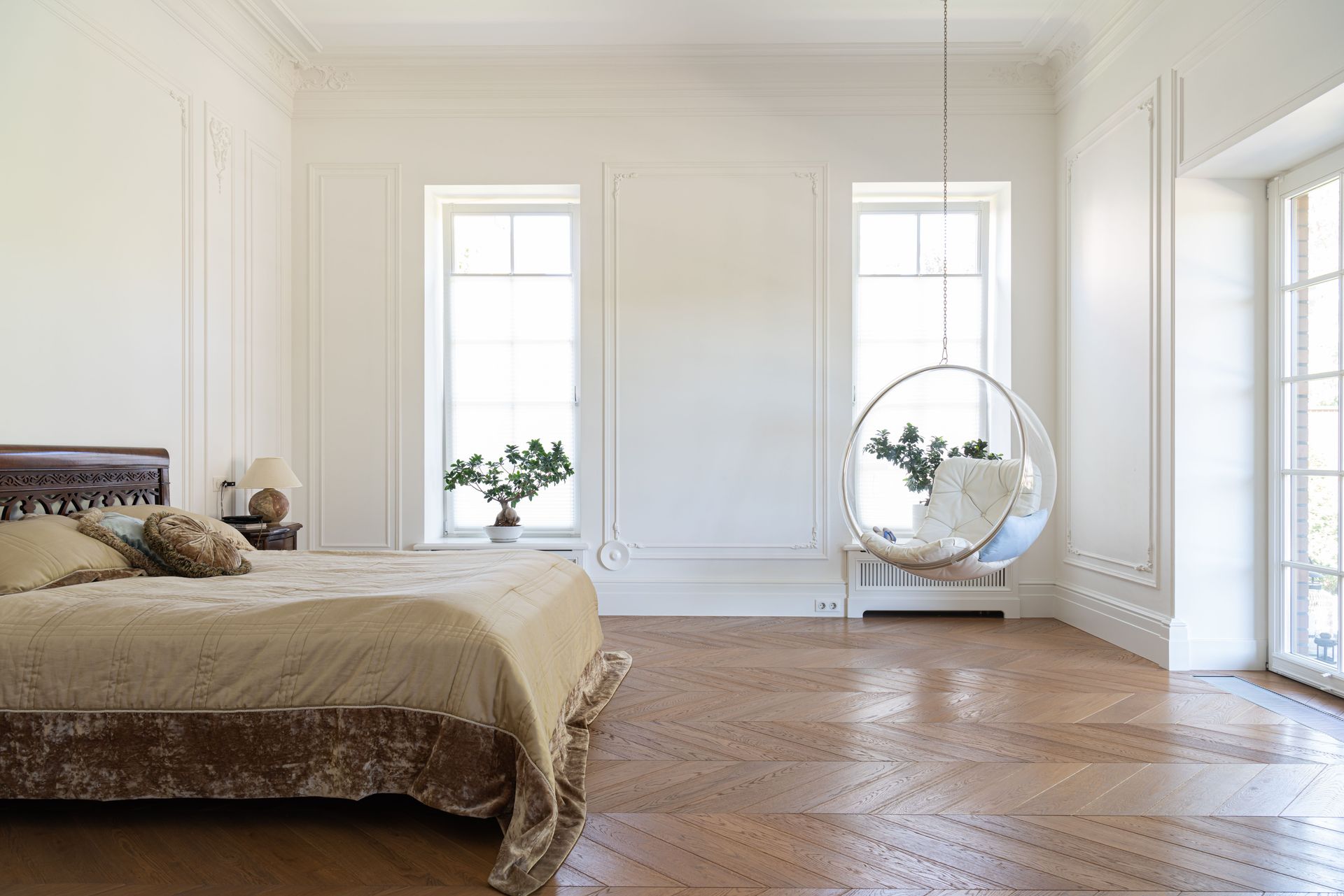 Bright minimalist bedroom with bed, large windows, wood floor, and a hanging chair