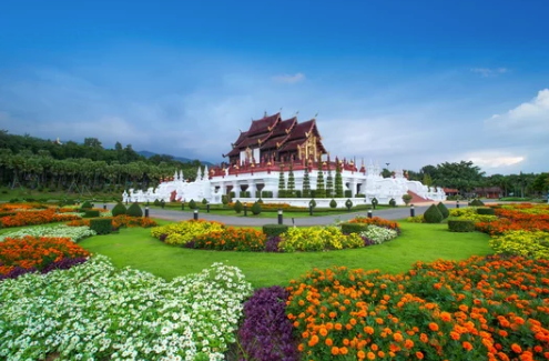 Colorful flower garden with a traditional temple on a hill under a blue sky